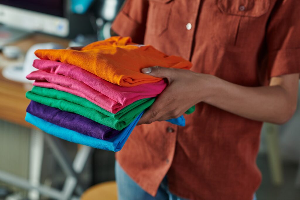 Cropped view of blurred young african american craftswoman holding clothes while standing