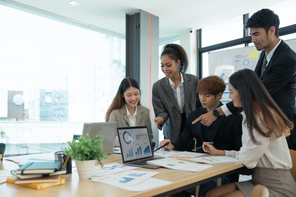 Diverse executive businesspeople discuss corporation financial plan at boardroom meeting table